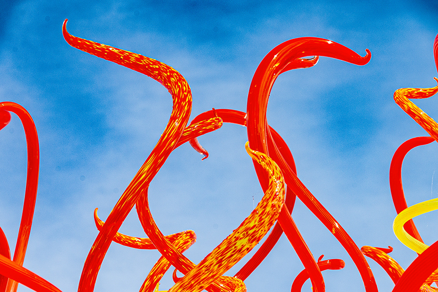 The image showcases vibrant, intertwined red and yellow structures against a clear blue sky, creating a striking and colorful visual effect.