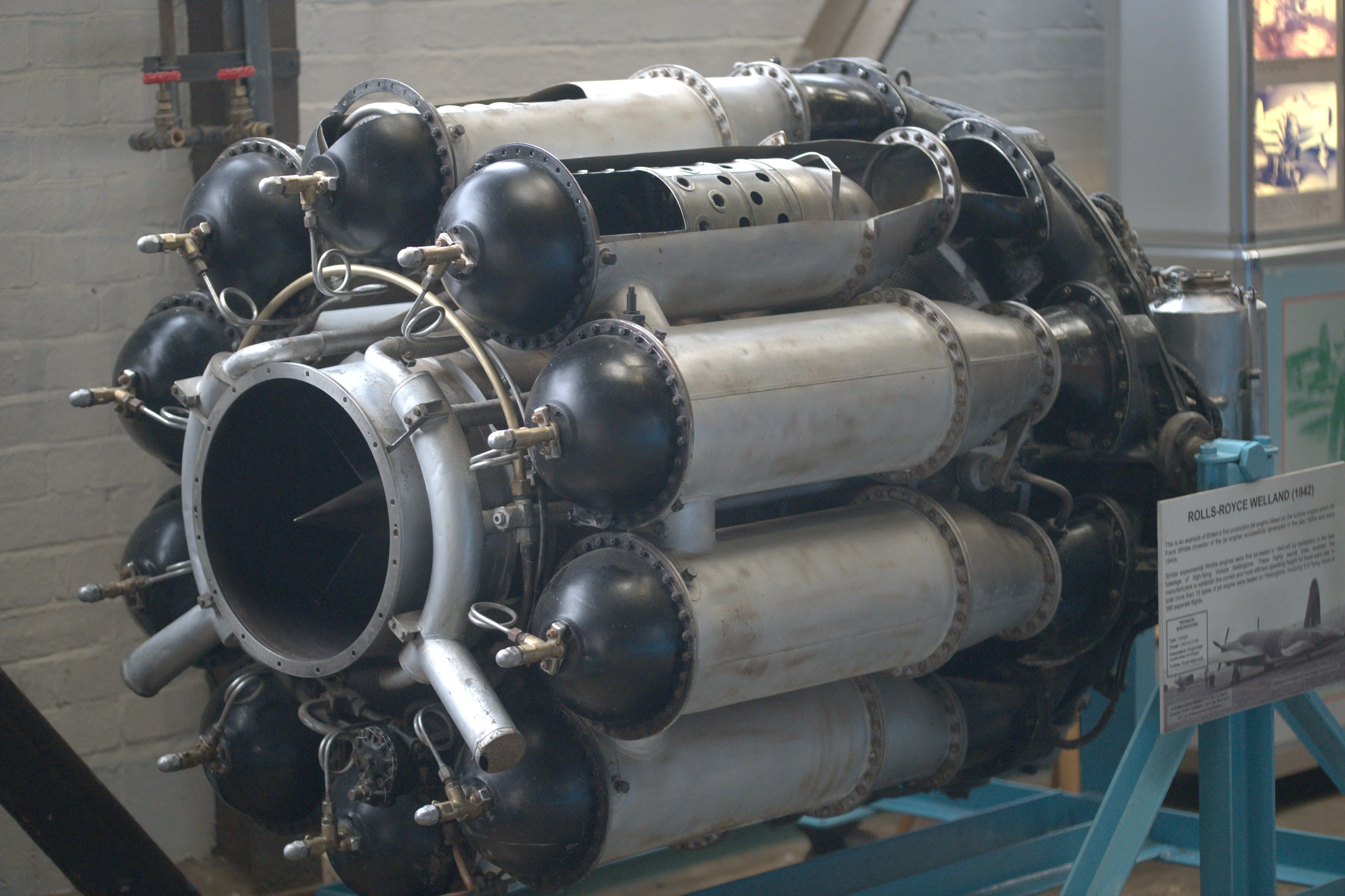 Rolls-Royce Welland turbojet engine displayed in a museum, showing its centrifugal compressor and reverse-flow combustion chambers.