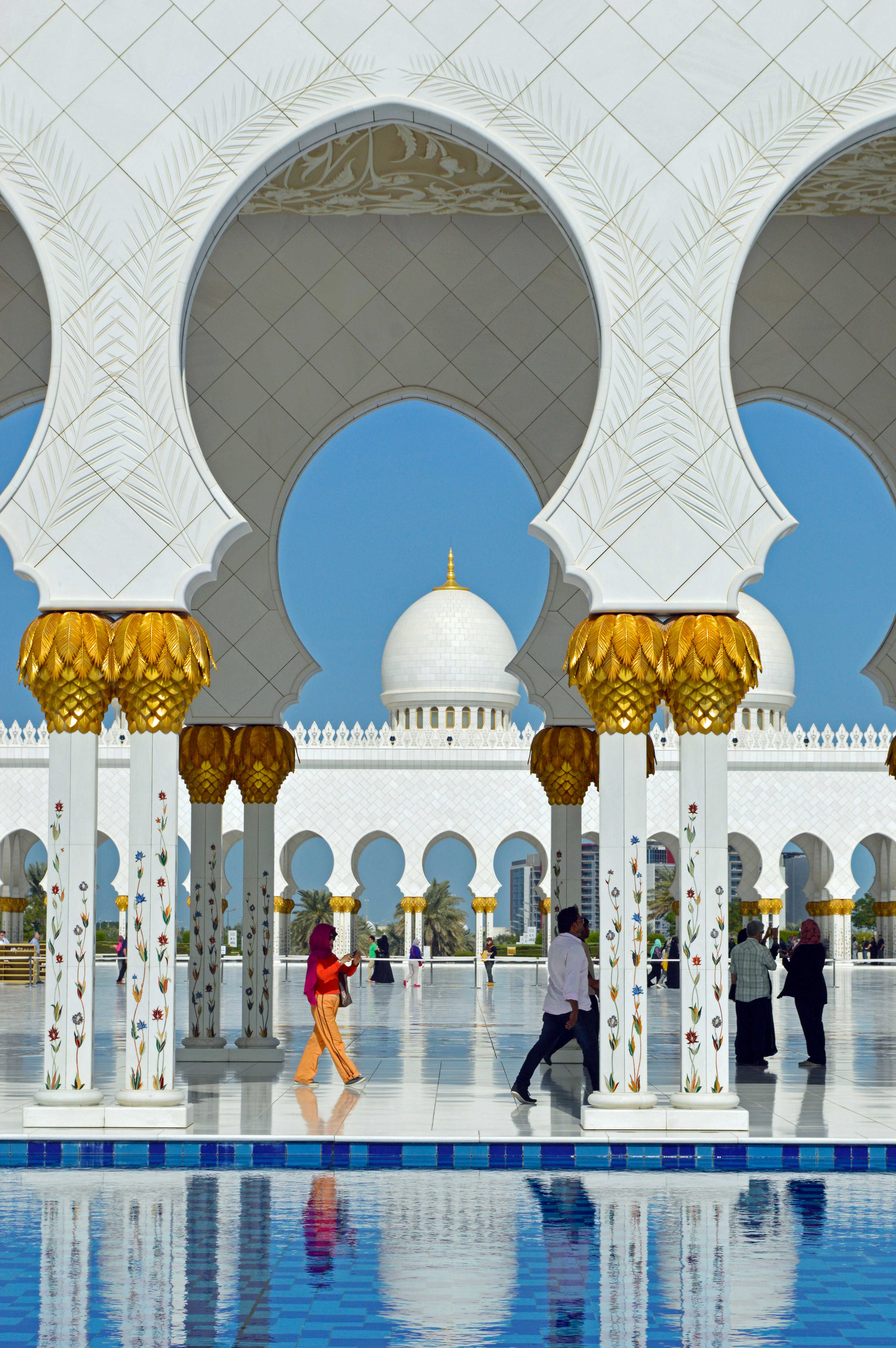 The courtyard features reflective water pools that enhance the mosque's majestic appearance